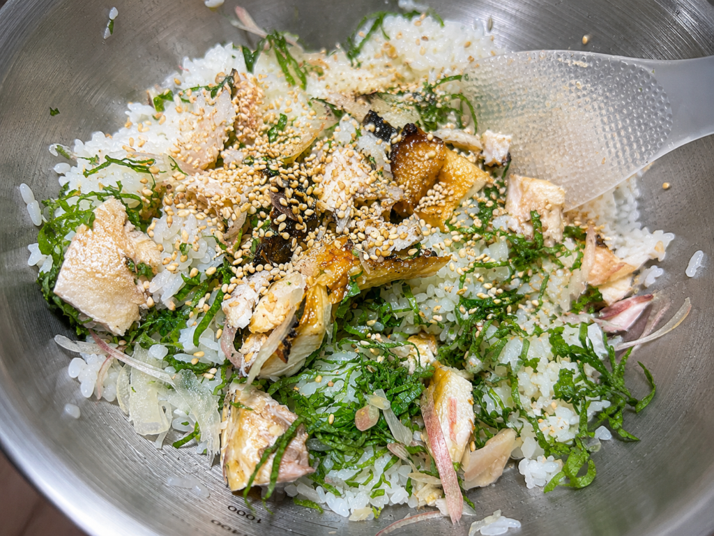 酢飯に焼いた塩サバを加えている様子