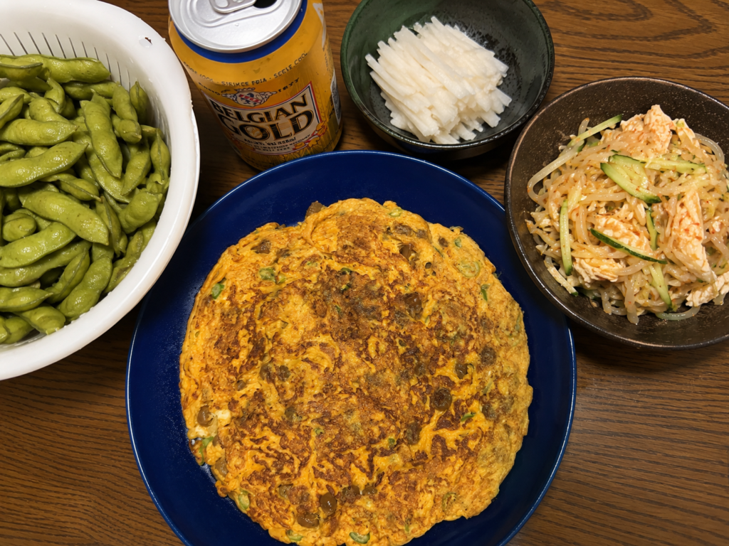 納豆卵焼きを中心に、生枝豆、細切り長芋、バンバンジー、ベルジャンゴールドを並べた家飲みの食卓
