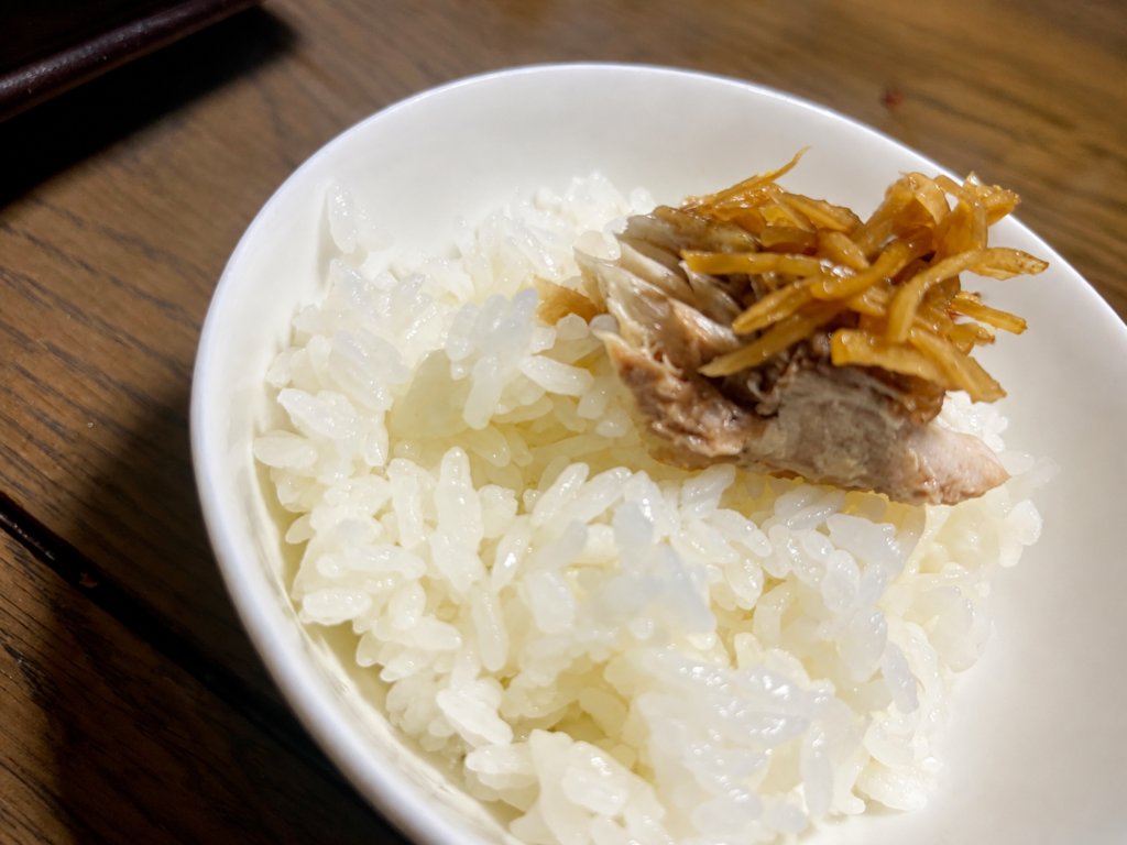 白いご飯に塩さばの身と煮汁を吸った生姜をのせた様子