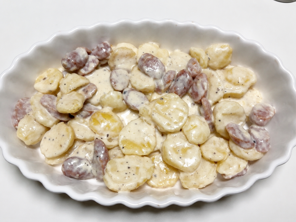 煮込んだじゃがいもとソーセージを楕円形の耐熱皿に移した様子