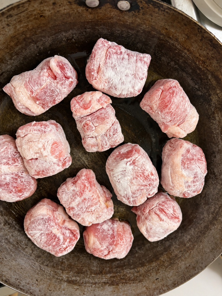フライパンで表面を焼き固めている豚こま厚揚げ肉巻き