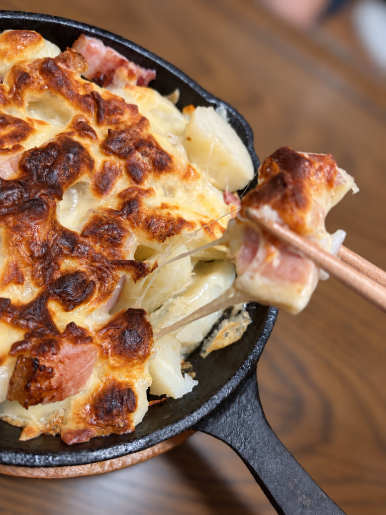 とろけたチーズが伸びるポテトチーズ焼きを箸で取り分けた様子