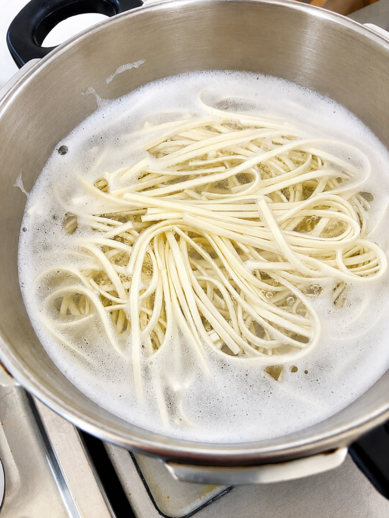 鍋で讃岐うどんの乾麺を茹でている様子