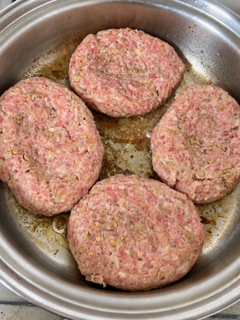 冷凍舞茸と玉ねぎを混ぜ込んだハンバーグ4個をフライパンに並べた様子