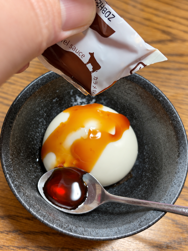 牧家白いプリンに付属のカラメルソースをかける様子
